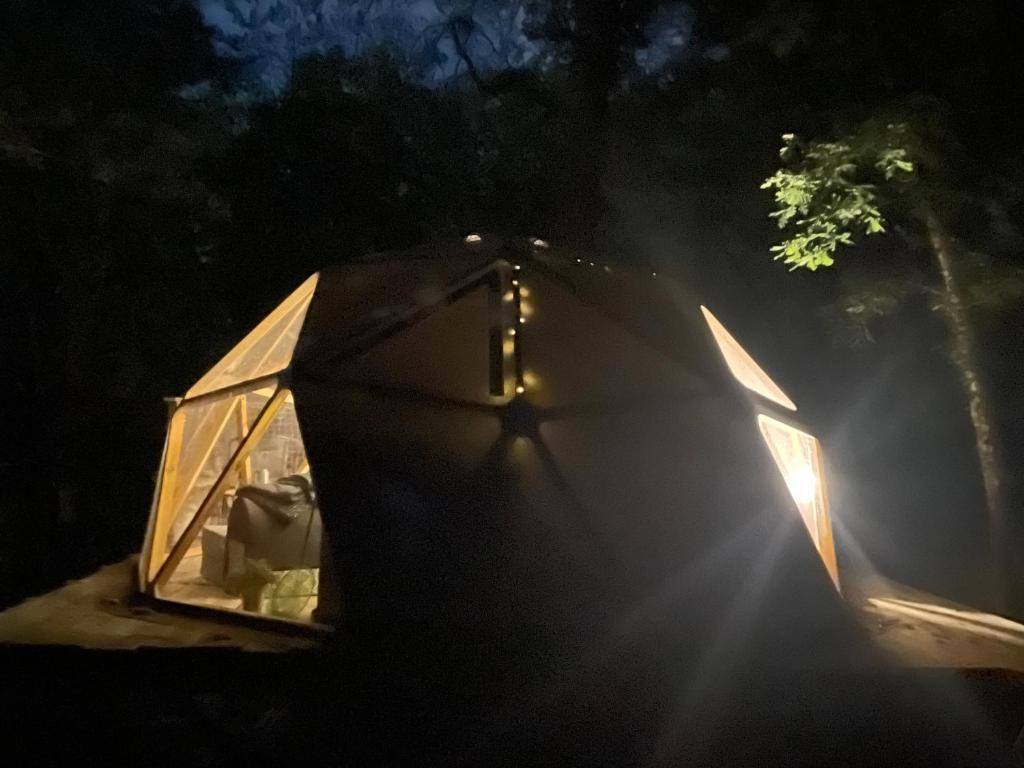 un igloo en verre avec le soleil qui brille dedans dans l'établissement Arborea, nuits insolites au cœur de la forêt, à Montignac