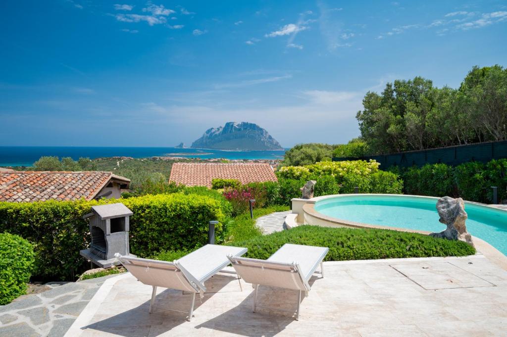 une maison avec une piscine et deux chaises longues dans l'établissement Villa Kiki - Klodge, à Costa Corallina