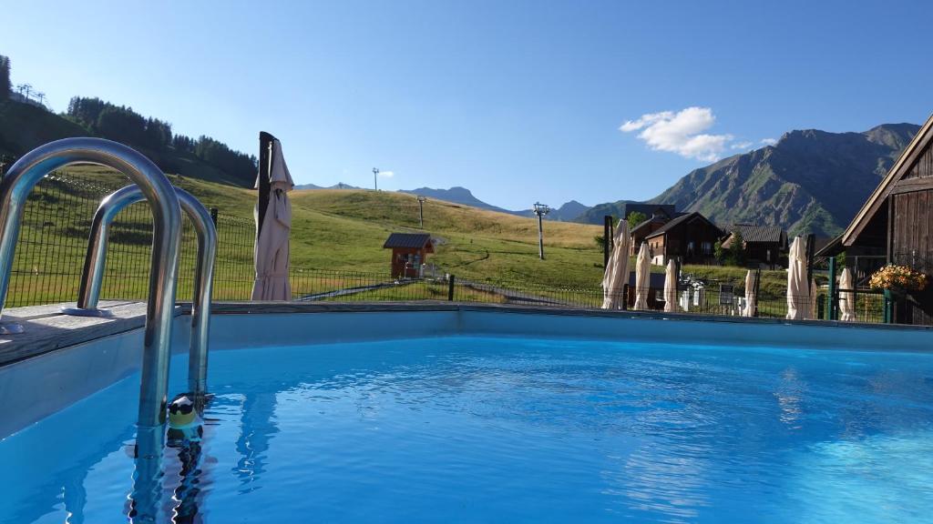 une piscine avec des montagnes en arrière-plan dans l'établissement Le Balcon des Ecrins, à Réallon