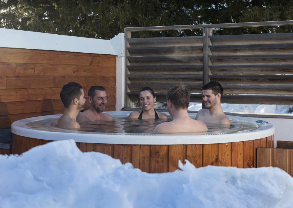 un groupe d'hommes assis dans un bain à remous dans l'établissement Charmant appartement confortable pour 6 personnes 40m2 pied pistes, Piscine, wifi, parking, à Chamrousse