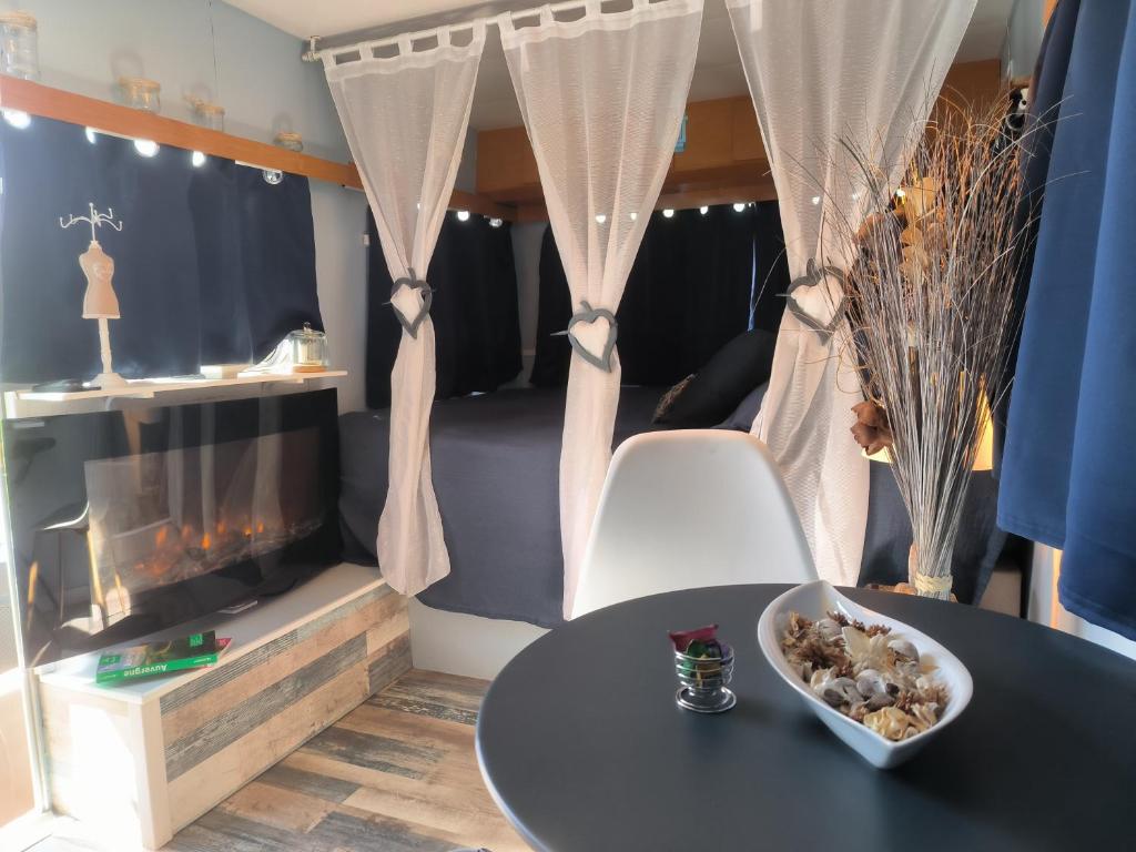 Cette chambre dispose d'une table et d'une cheminée. dans l'établissement Caravane Seventies avec jacuzzi, à Lapalisse