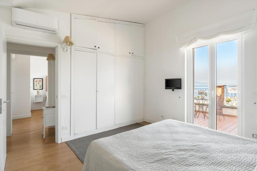 une chambre blanche avec un lit et un balcon dans l'établissement Villa Giu Giu vista mare con piscina a Sorrento, à Sorrente
