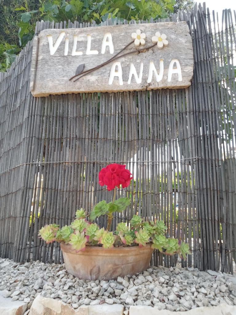 un panneau sur une clôture avec une fleur rouge dans un pot dans l'établissement Villa Anna Polignano, à Polignano a Mare
