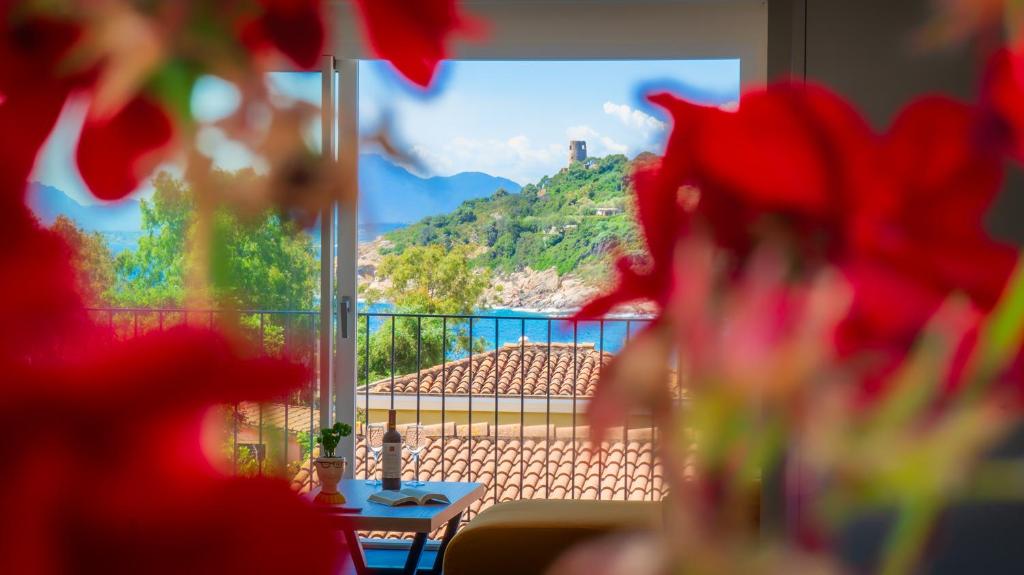une table avec des fleurs rouges devant une fenêtre dans l'établissement Villa Manzoni, à Àrbatax 45 autres photos