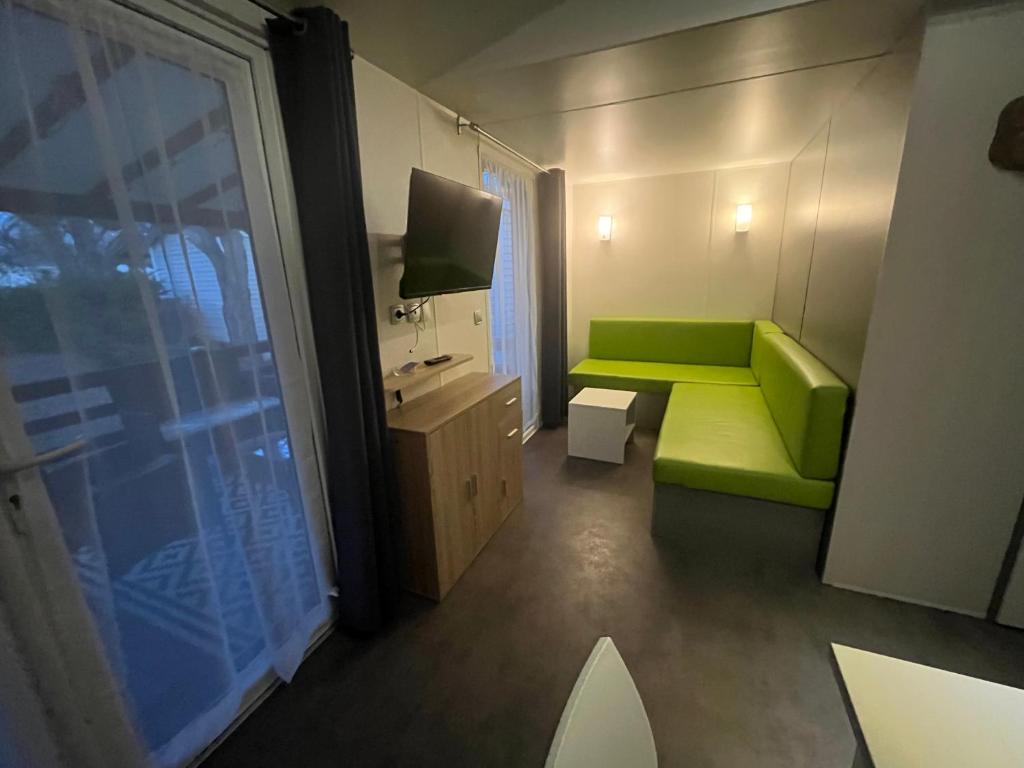 un salon avec un canapé vert et une télévision dans l'établissement Mobil home, à Sainte-Croix-de-Verdon