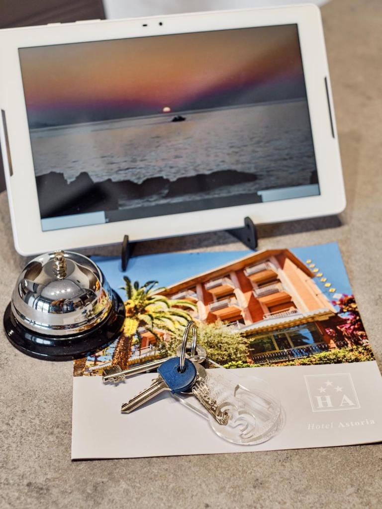 une table avec un ordinateur portable et des clés et une tablette dans l'établissement Hotel Astoria, à Bordighera 31 autres photos