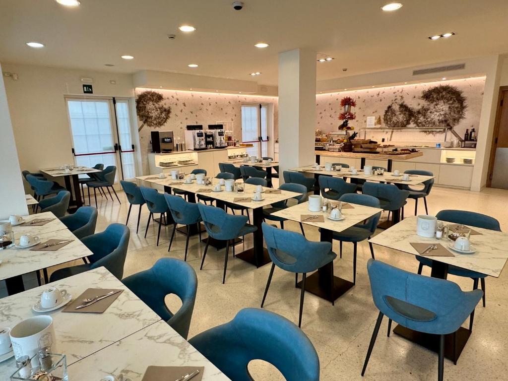 une salle à manger avec des tables et des chaises bleues dans l'établissement Hotel Castiglione, à Lignano Sabbiadoro