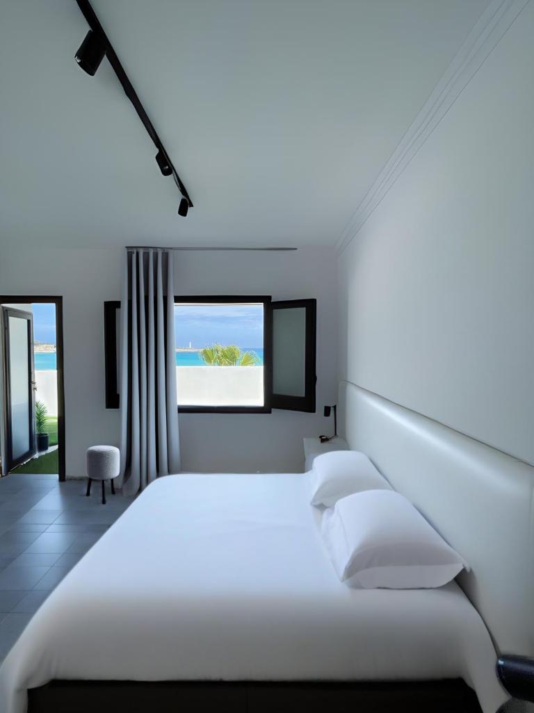 une chambre blanche avec un lit et une fenêtre dans l'établissement Hotel Egitarso Sul Mare, à San Vito Lo Capo