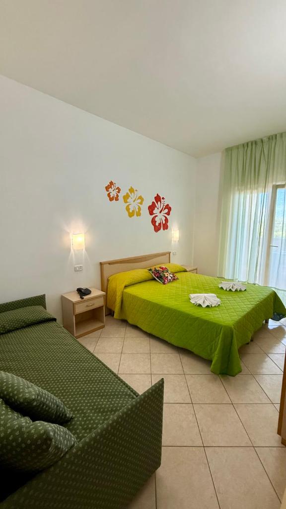 - une chambre avec un lit vert et un canapé dans l'établissement Ibisco Hotel, à Rodi Garganico