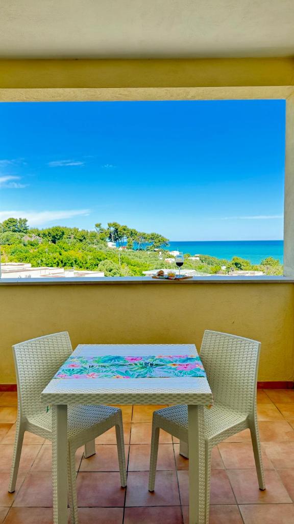 une table et deux chaises devant une fenêtre dans l'établissement Ibisco Hotel, à Rodi Garganico