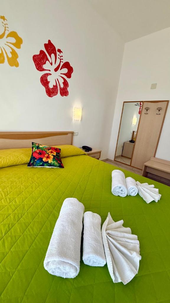 - un lit vert avec des serviettes blanches dans l'établissement Ibisco Hotel, à Rodi Garganico