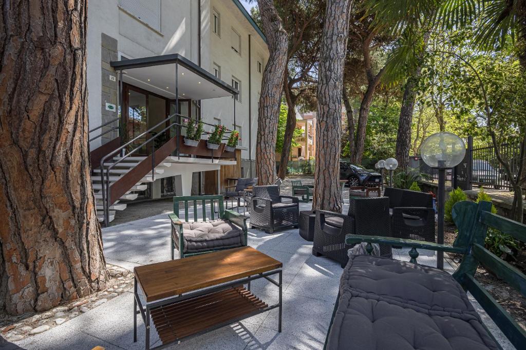 un patio avec des tables, des chaises et des arbres dans l'établissement Hotel Levante Cesenatico, à Cesenatico