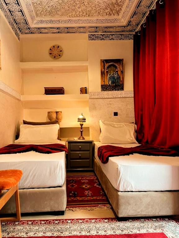deux lits dans une chambre avec des rideaux rouges dans l'établissement Riad Lalla Marrakech, à Marrakech