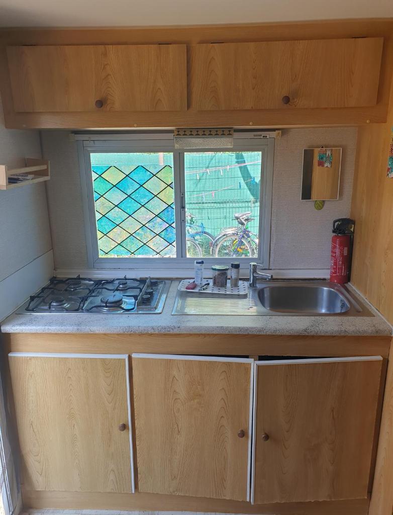 une petite cuisine avec un évier et une fenêtre dans l'établissement Mobil home chez un particulier pour 1 à 4 personnes à 800 m de la plage de Valras pas dans un camping, à Sérignan