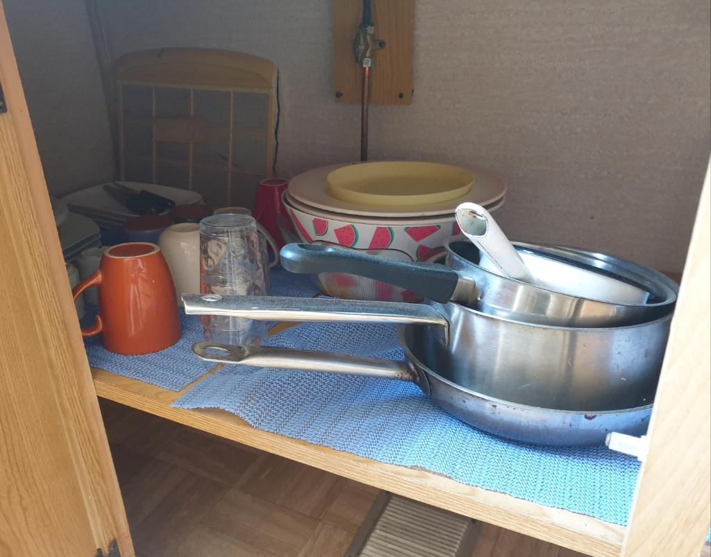 - une étagère de cuisine avec une poêle et des bols dans l'établissement Mobil home chez un particulier pour 1 à 4 personnes à 800 m de la plage de Valras pas dans un camping, à Sérignan
