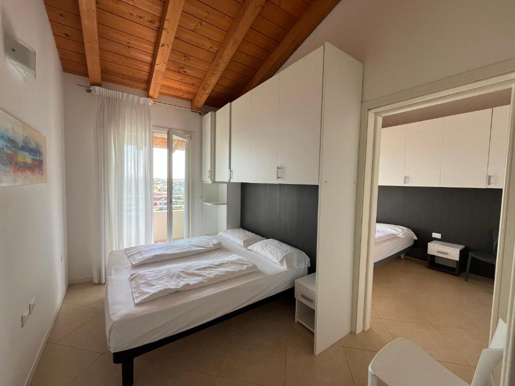 une chambre avec un lit et des armoires blanches et une fenêtre dans l'établissement Villaggio Hemingway - Family Aparthotel, à Caorle 164 autres photos