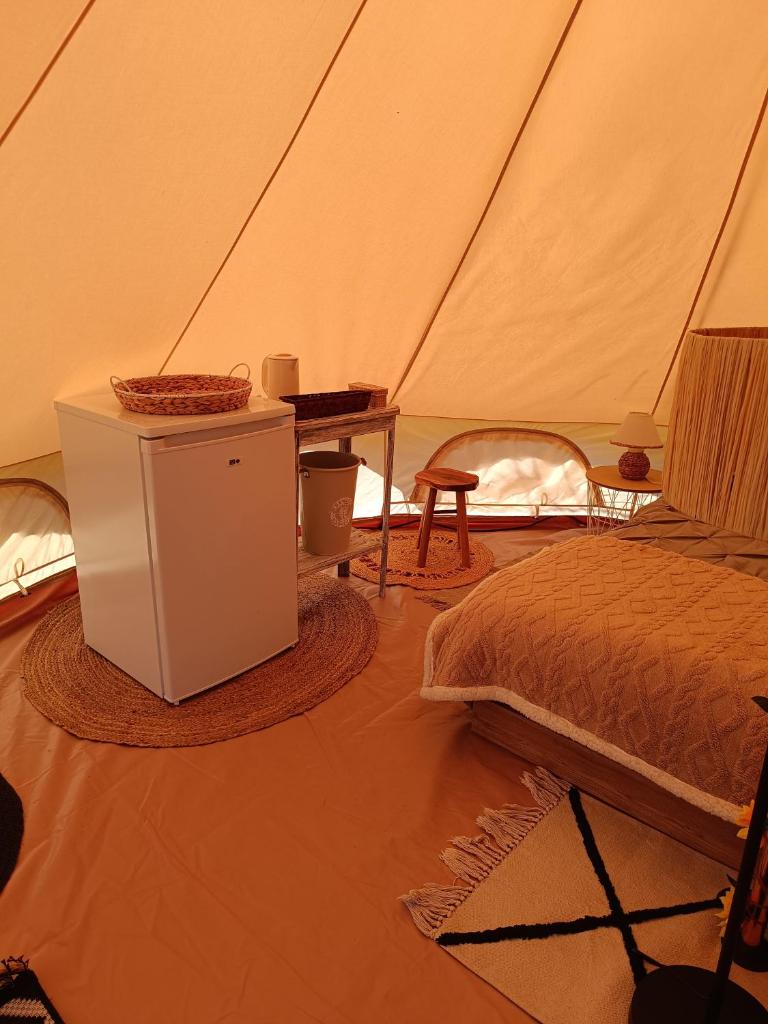 - une chambre avec un lit et une table dans une tente dans l'établissement Tente mongole " ô Rêves Atypiques", à Boucé