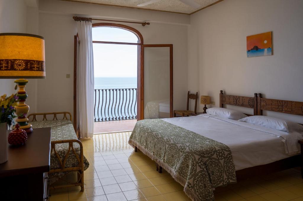 une chambre avec un lit et une grande fenêtre dans l'établissement Hotel Carasco, à Lipari