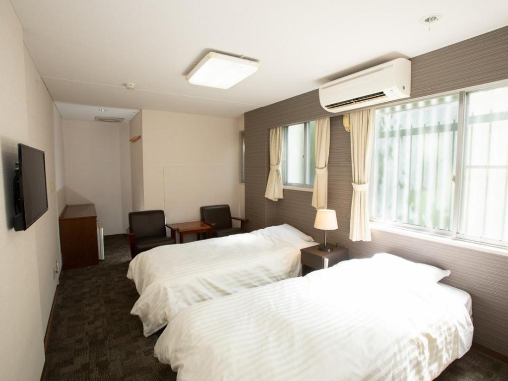 une chambre d'hôtel avec deux lits et une fenêtre dans l'établissement Itoen Hotel Inatori, à Inatori
