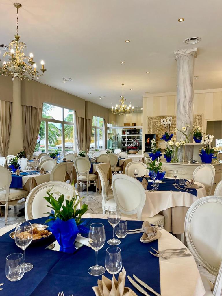 une salle à manger avec des tables et des chaises blanches dans l'établissement Hotel La Pigna, à Marina di Pietrasanta