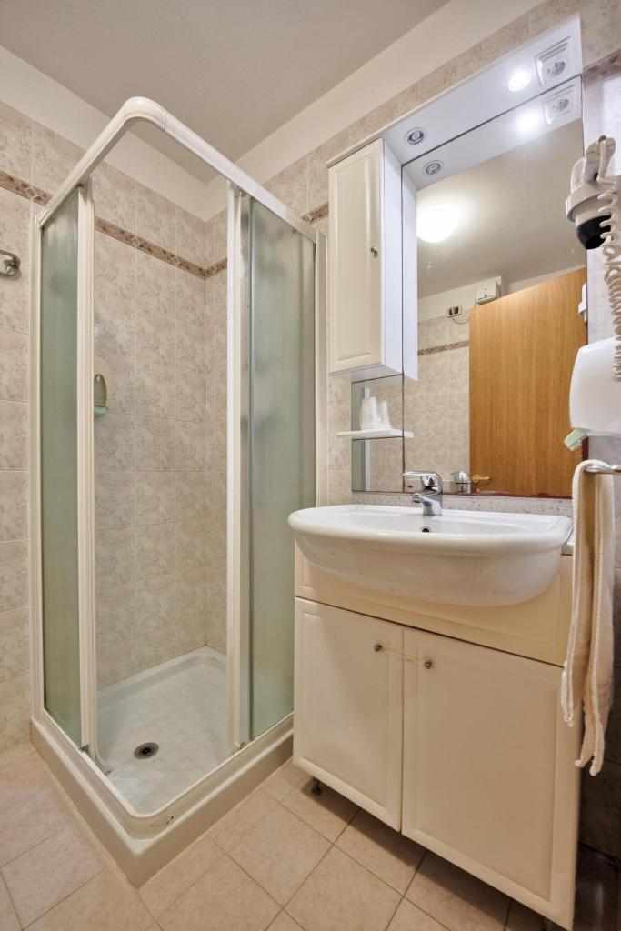 une salle de bain avec douche et lavabo dans l'établissement Hotel Flora, à Lignano Sabbiadoro 43 autres photos