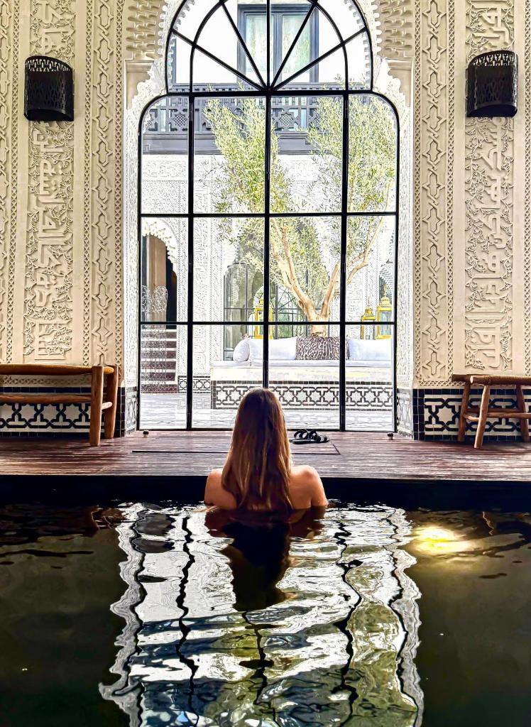 une femme assise dans un bassin d'eau dans un bâtiment dans l'établissement Riad Kheirredine, à Marrakech