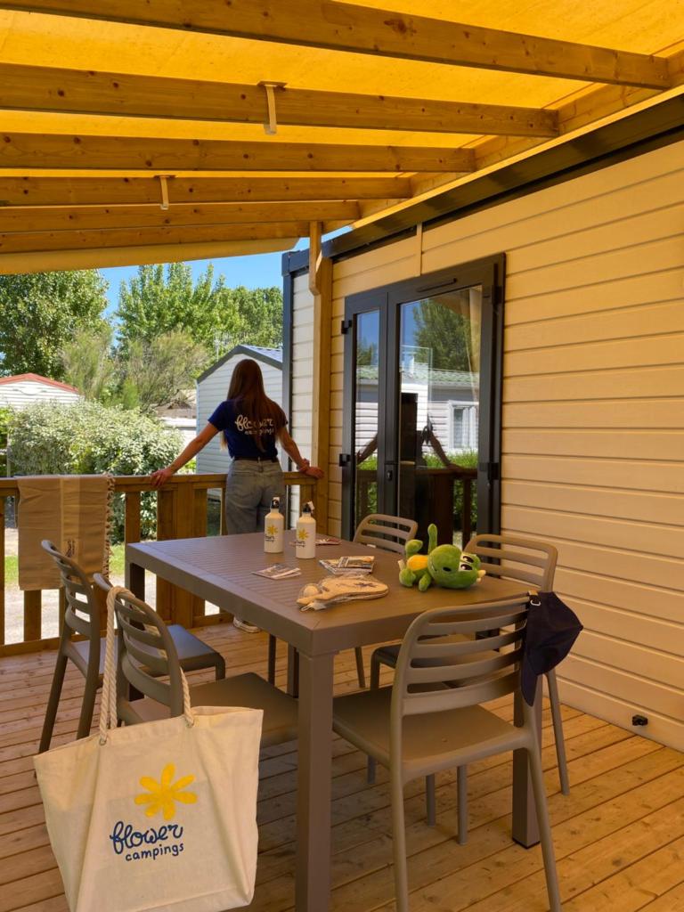 une femme debout sur une terrasse avec une table et des chaises dans l'établissement Domaine Résidentiel de Plein Air Escale du Perthuis, à La Tranche-sur-Mer