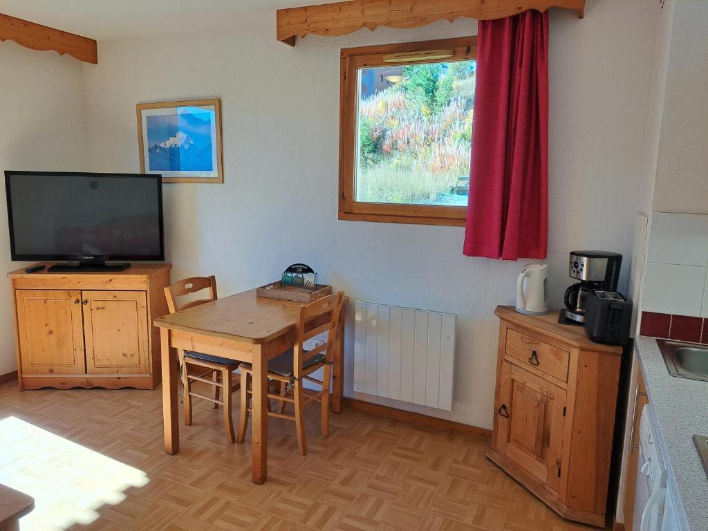 un salon avec une table et une télévision dans l'établissement Appartement avec balcon - 2 personnes, à Puy-Saint-Vincent