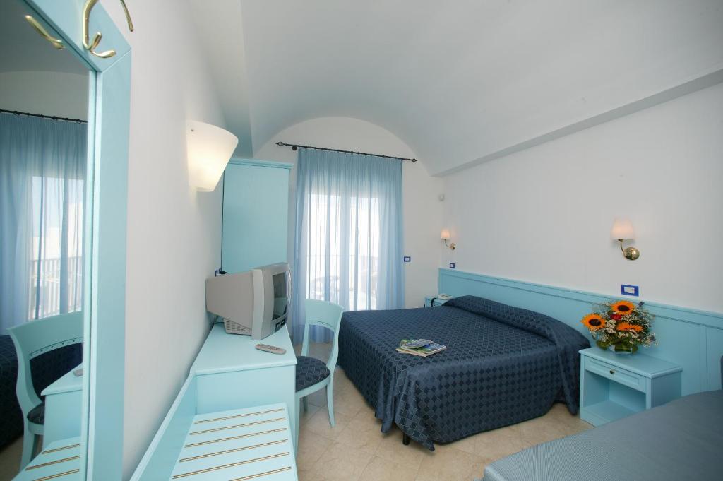 une chambre avec un lit bleu et un miroir dans l'établissement Hotel Elisa - Spiaggia Privata Inclusa, à Peschici