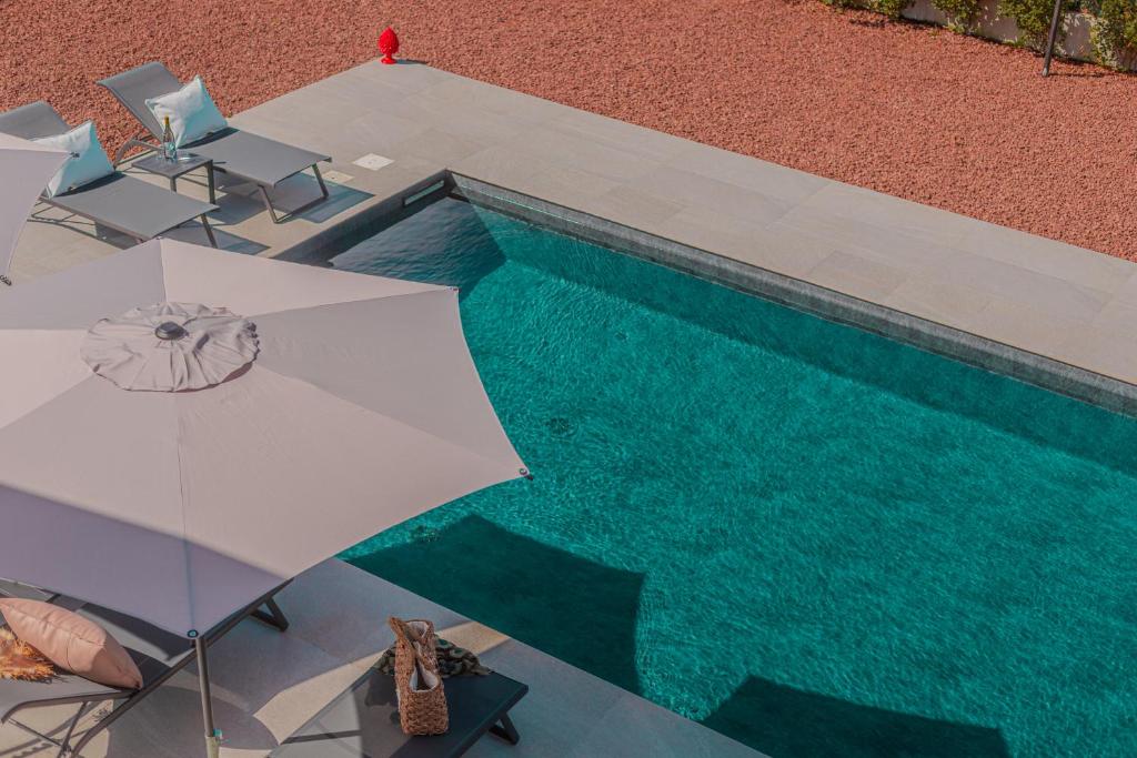 une piscine avec deux parasols et une piscine dans l'établissement NAHIA Collection Villa, à Campofelice di Roccella 52 autres photos