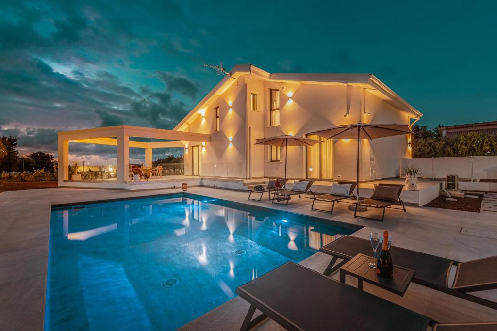 une villa avec une piscine la nuit dans l'établissement NAHIA Collection Villa, à Campofelice di Roccella
