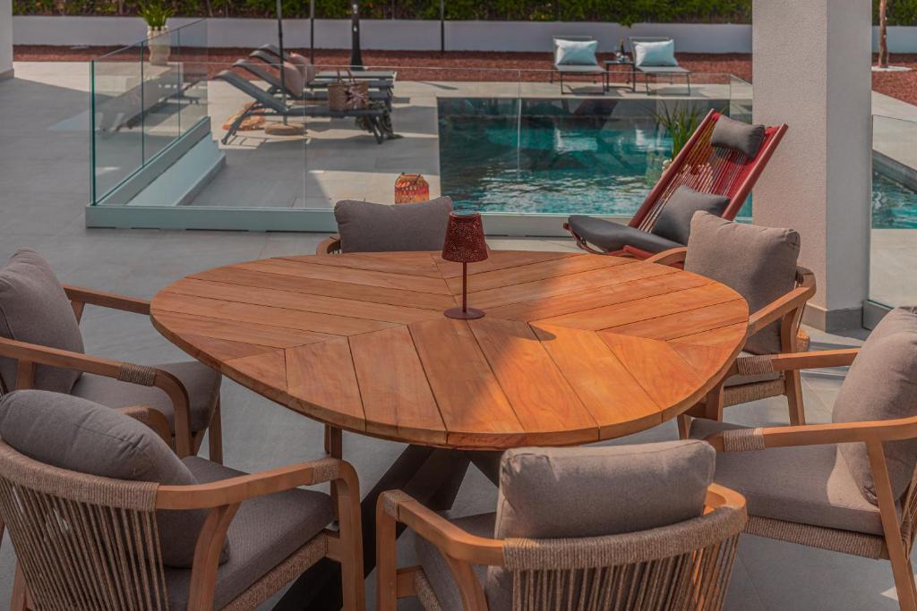 une table et des chaises en bois ainsi qu'une piscine dans l'établissement NAHIA Collection Villa, à Campofelice di Roccella