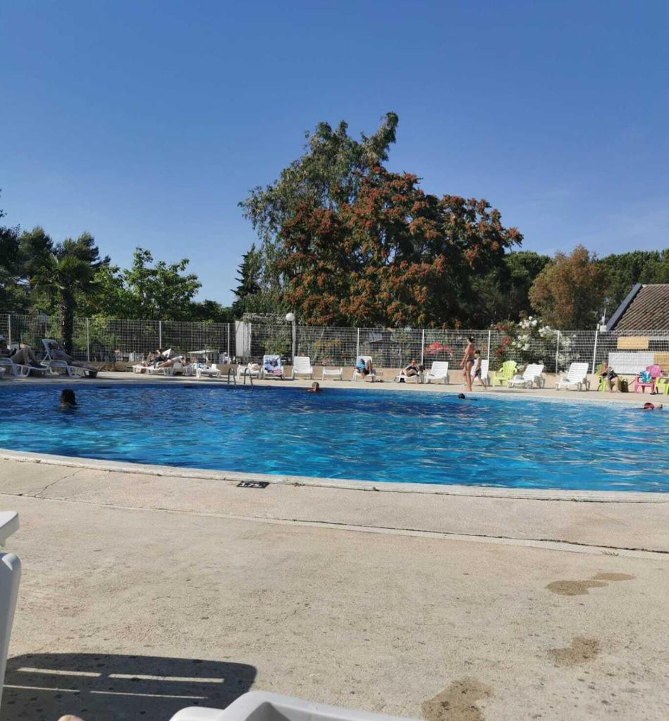 une grande piscine bleue avec des gens dedans dans l'établissement Céline et Alain, mobil Home cosy, à La Roque-dʼAnthéron