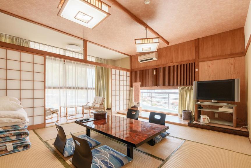 un salon avec une table et une télévision dans l'établissement 熱海来宮の湯 松月, à Atami