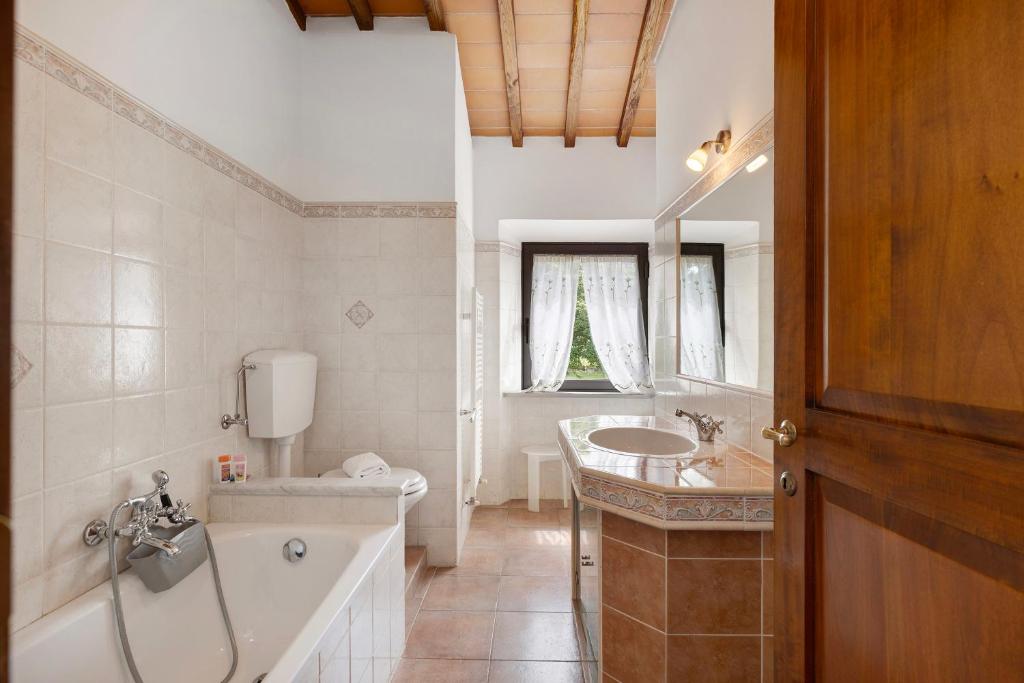 une salle de bain avec une baignoire, un lavabo et des toilettes dans l'établissement Podere Beccalorzo con piscina, à San Donato in Poggio