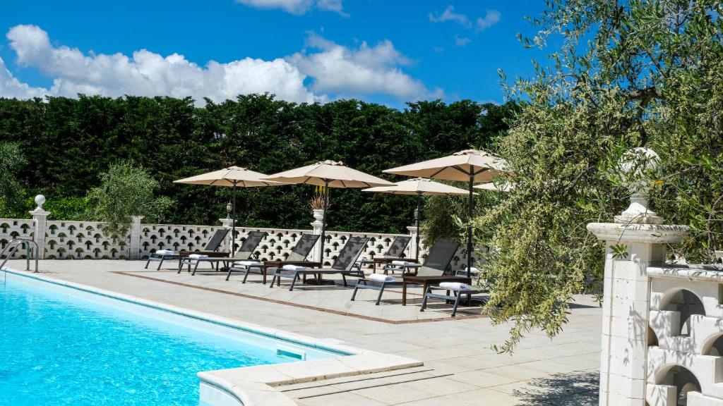 une piscine avec tables, chaises et parasols dans l'établissement Villa Poggio di Luna con piscina privata, à Peschici