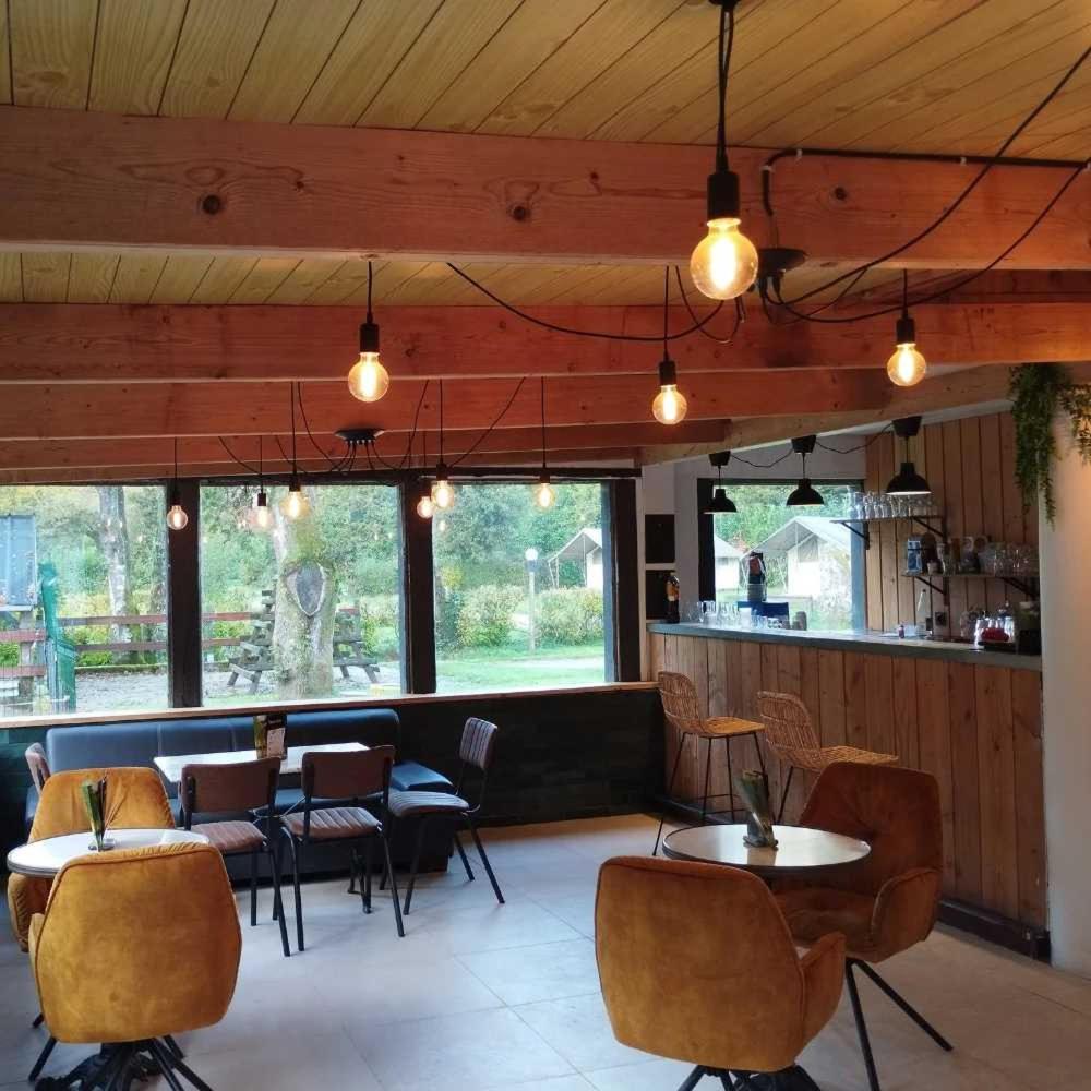 un restaurant avec plusieurs tables, chaises et lumières dans l'établissement Camping 3 étoiles - Piscine - ccafbbc, à Huelgoat 37 autres photos