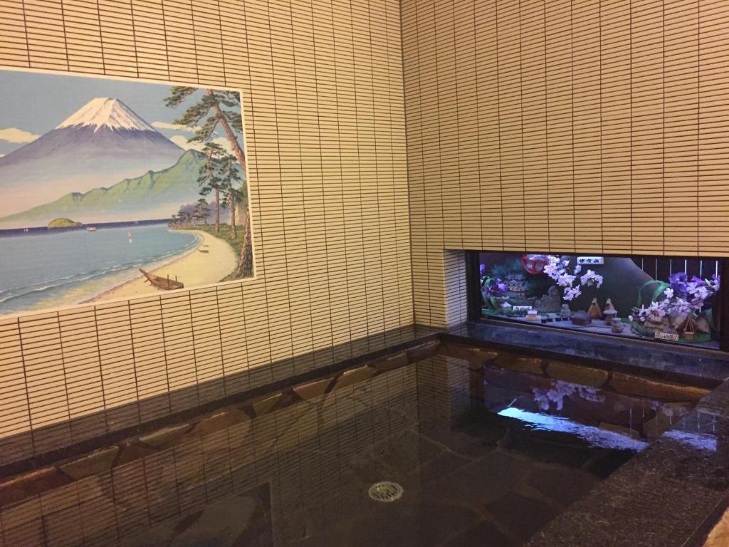 une chambre avec une télévision et un tableau sur le mur dans l'établissement Tobaya Ryokan, à Hikone