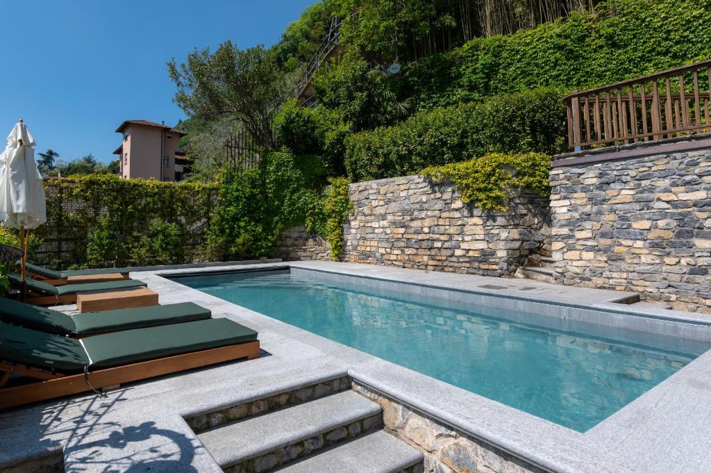 une piscine avec des escaliers et un mur en pierre dans l'établissement Ruby Como Villa with Lake View By Petra Luxury, à Laglio
