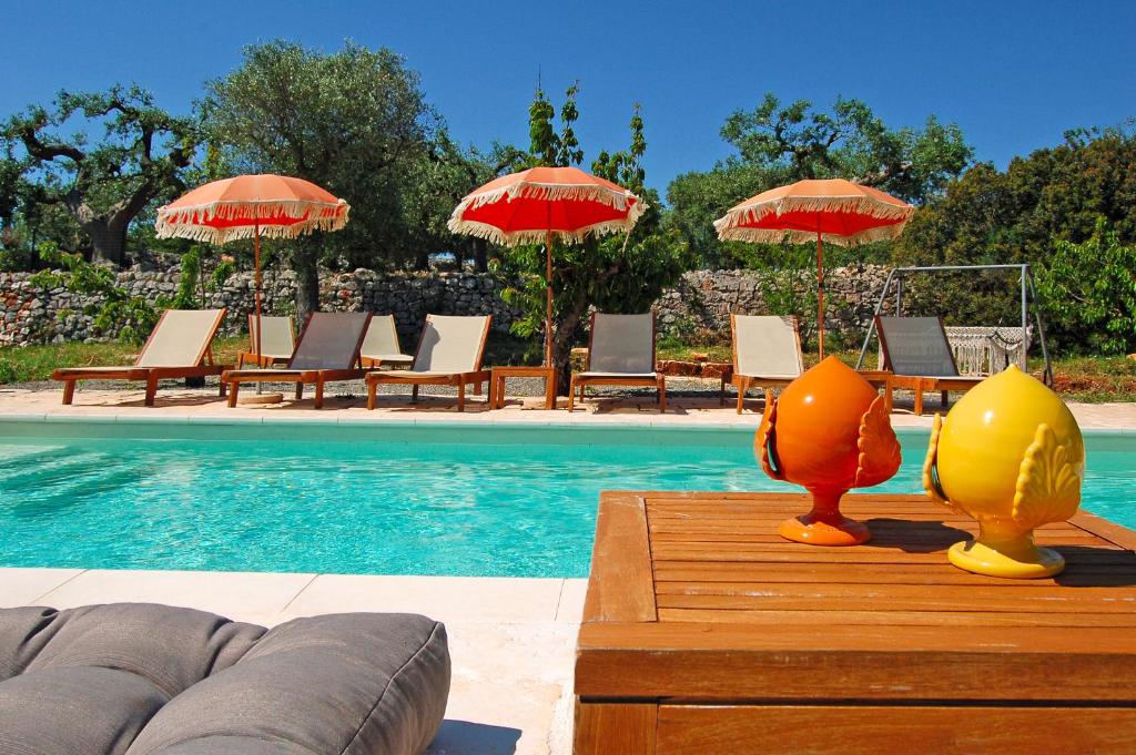 - une piscine avec des chaises longues et des parasols à côté de la piscine dans l'établissement Trullo Raro, à Padresergio 57 autres photos