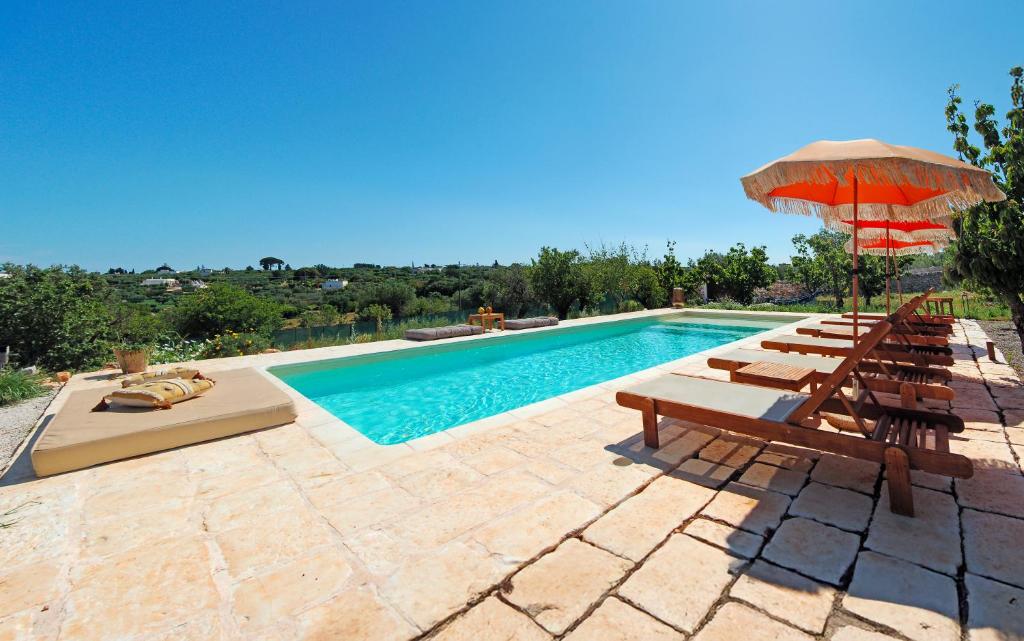 une piscine avec des chaises longues et un parasol dans l'établissement Trullo Raro, à Padresergio