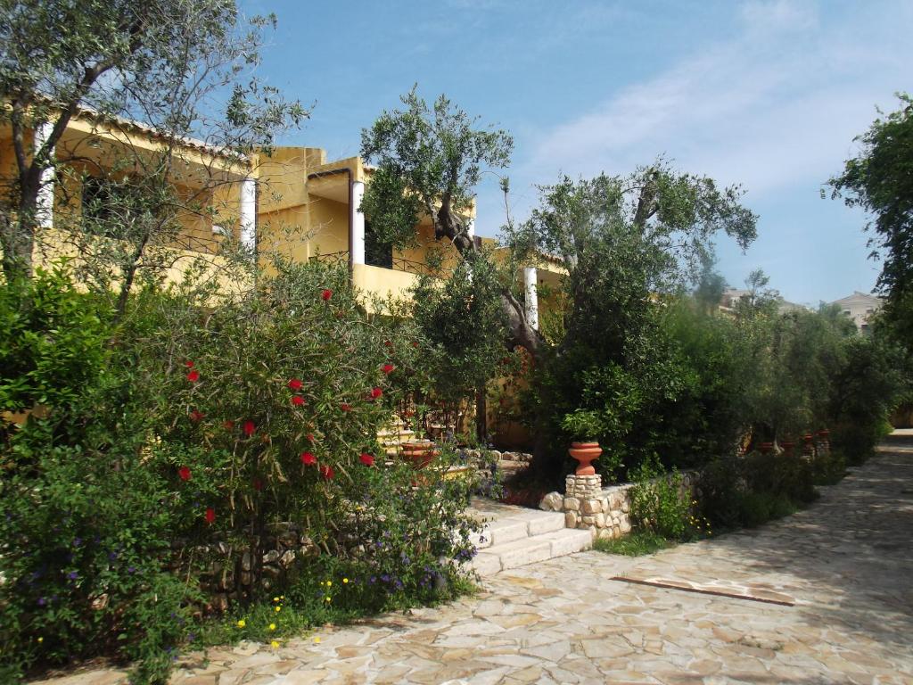 une maison avec un jardin planté de fleurs rouges et d'arbres dans l'établissement Hotel Resort Poggio degli Ulivi, à Rodi Garganico
