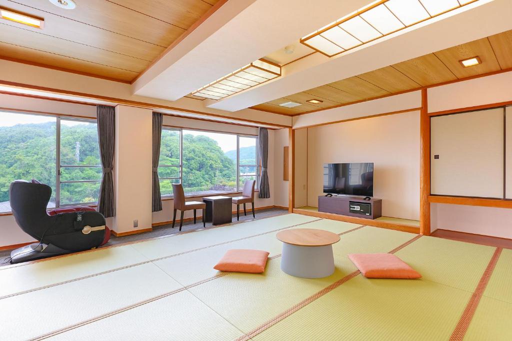 un salon avec une télévision, une table et des chaises dans l'établissement Ooedo Onsen Monogatari Premium Iseshima, à Shima