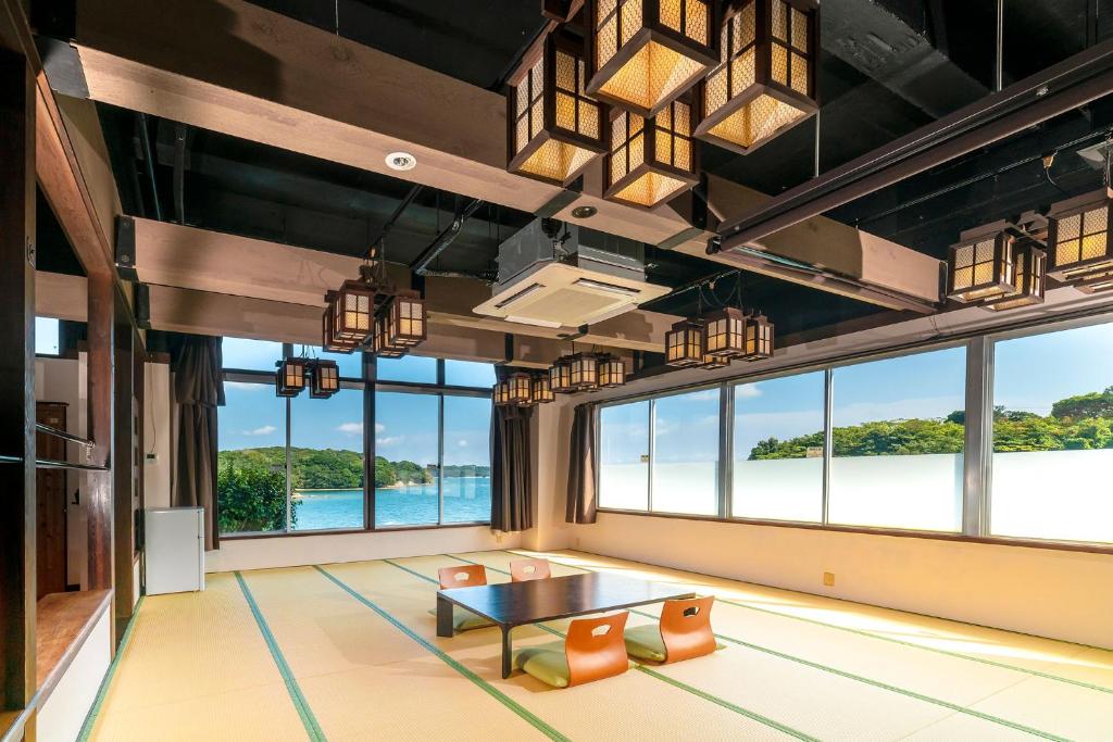 Cette grande chambre dispose d'une table, de chaises et de grandes fenêtres. dans l'établissement Ooedo Onsen Monogatari Premium Iseshima, à Shima
