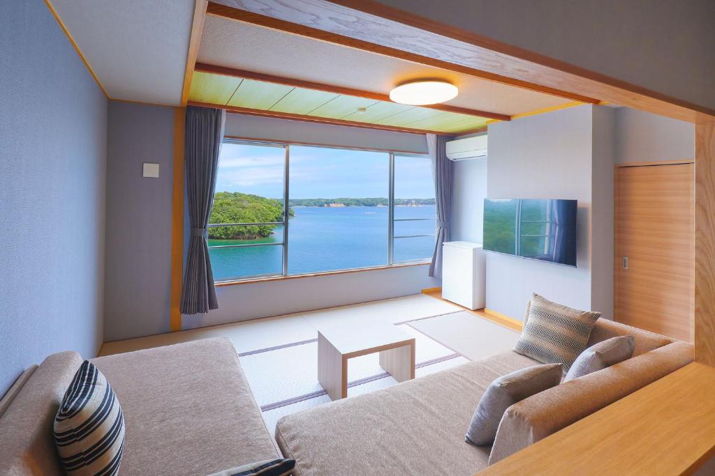 un salon avec un canapé et une grande fenêtre dans l'établissement Ooedo Onsen Monogatari Premium Iseshima, à Shima