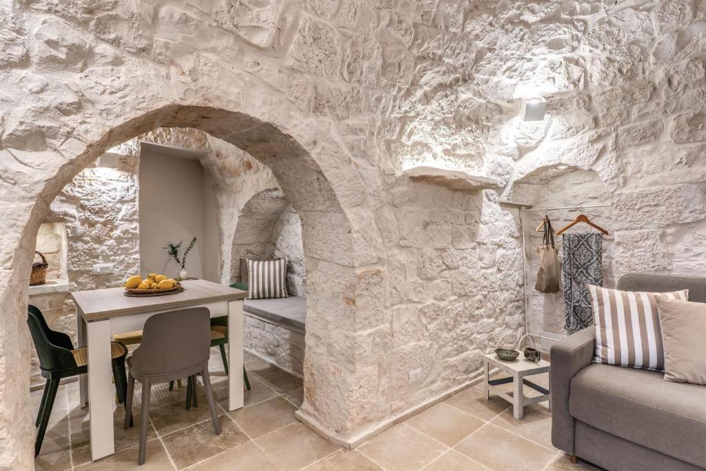 un salon avec une table et un mur en pierre dans l'établissement Trullo The Cove, à Ceglie Messapica