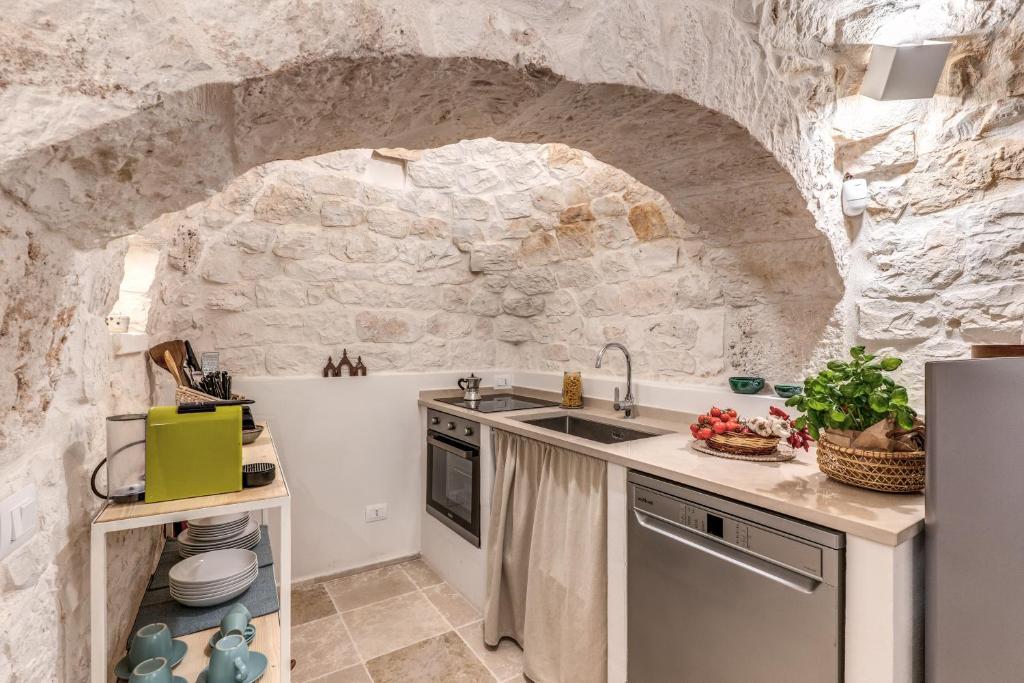 une cuisine avec un évier et un mur en pierre dans l'établissement Trullo The Cove, à Ceglie Messapica