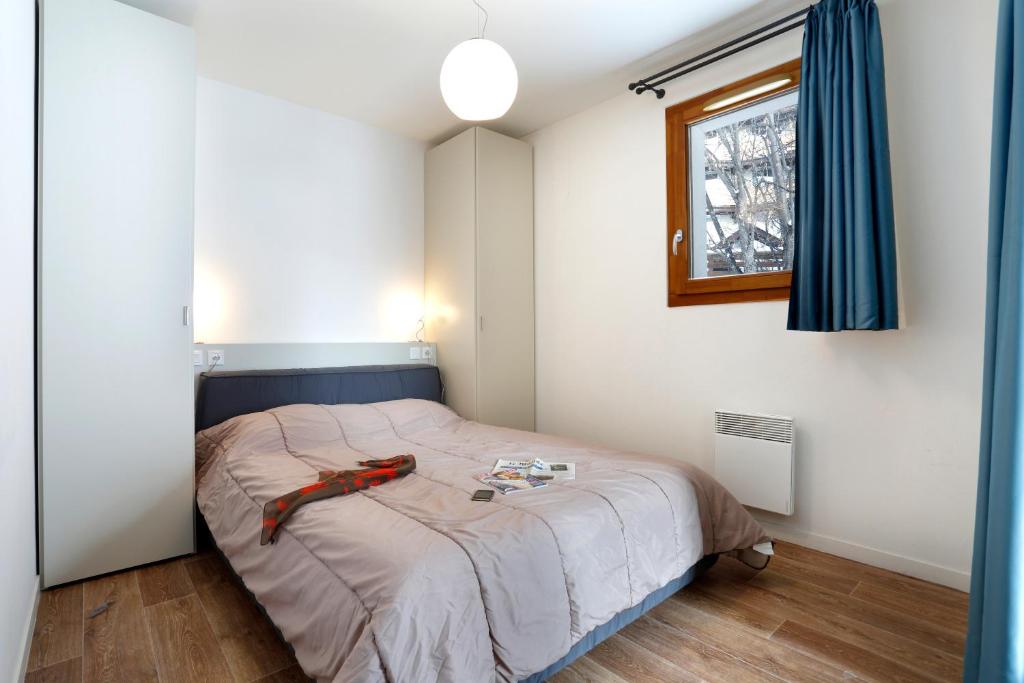 - une chambre avec un lit doté d'une tête de lit bleue et d'une fenêtre dans l'établissement Vacancéole - Au Coeur des Ours, à Les Deux Alpes