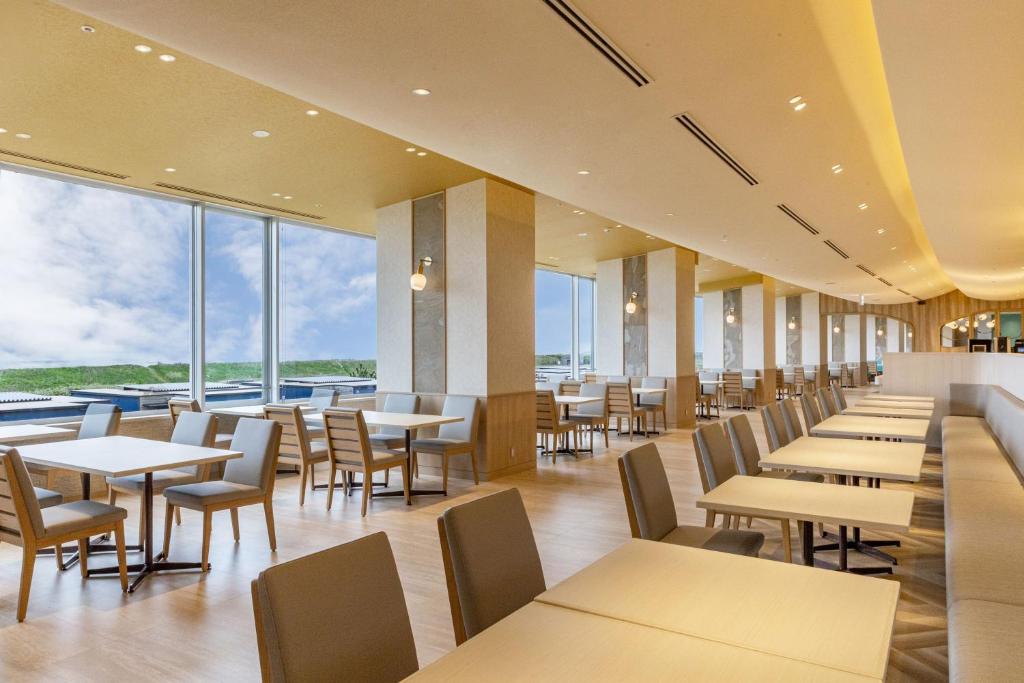 un restaurant avec des tables et des chaises et de grandes fenêtres dans l'établissement KAMENOI HOTEL Kujukuri, à Asahi 37 autres photos