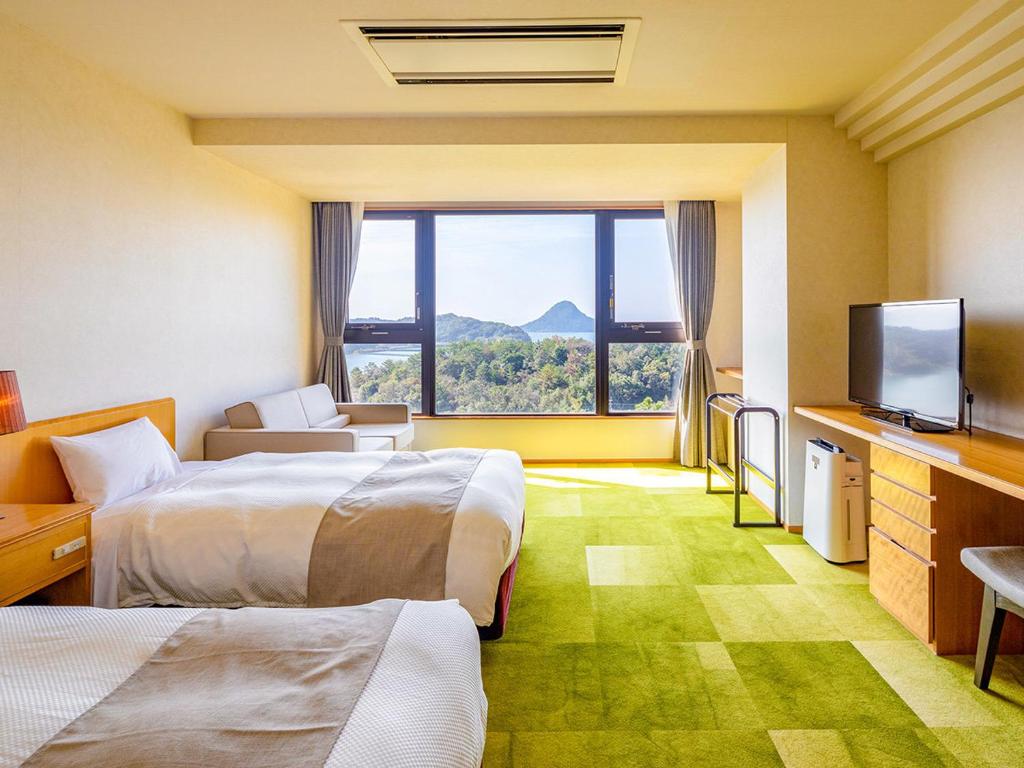 une chambre d'hôtel avec deux lits et une télévision à écran plat dans l'établissement Ooedo Onsen Monogatari Amakusa Hotel Kameya, à Kami Amakusa